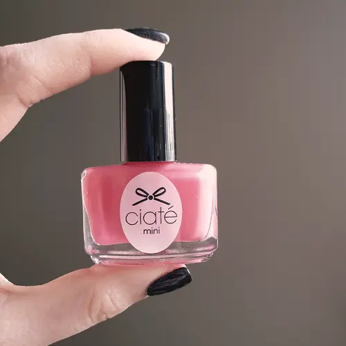 Frasco de esmalte rosado en la mano (foto ilustrativa)
