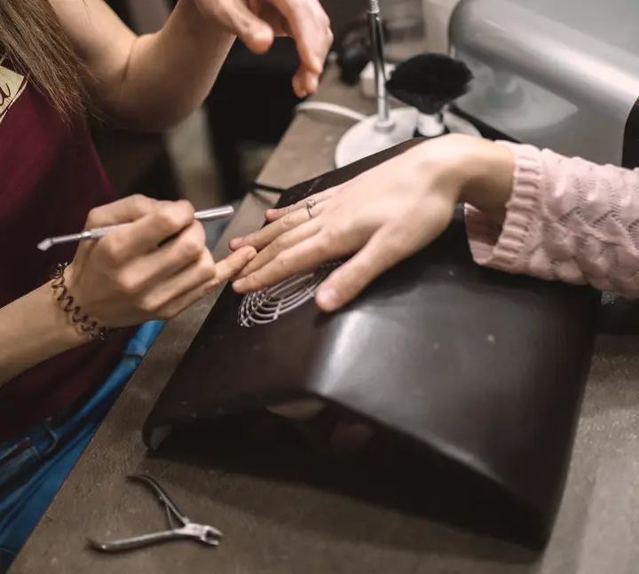 Manicurista haciendo un diseño en la mesa de manicure (foto ilustrativa)
